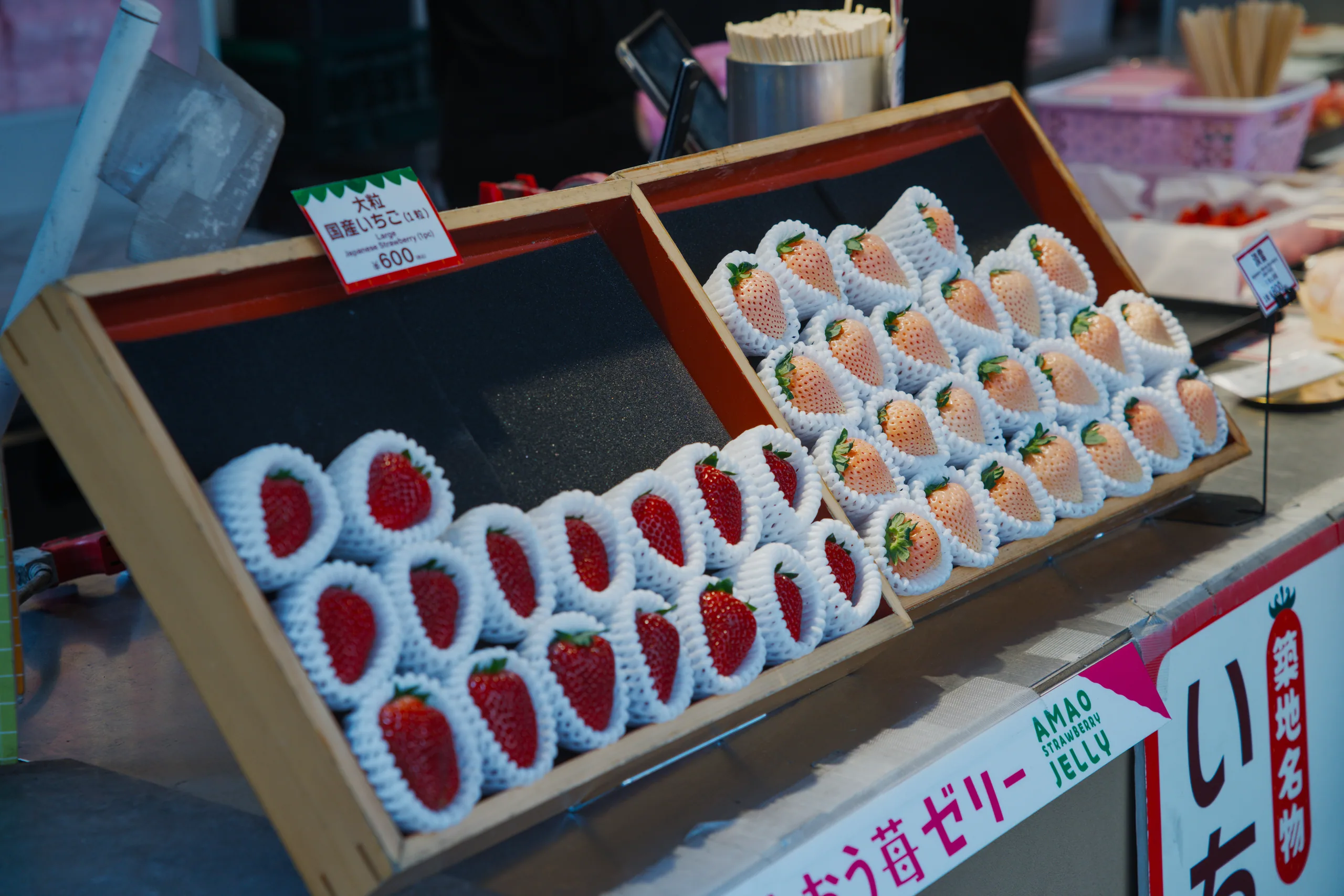 Boxes of individually wrapped strawberries stacked in a retail produce display.