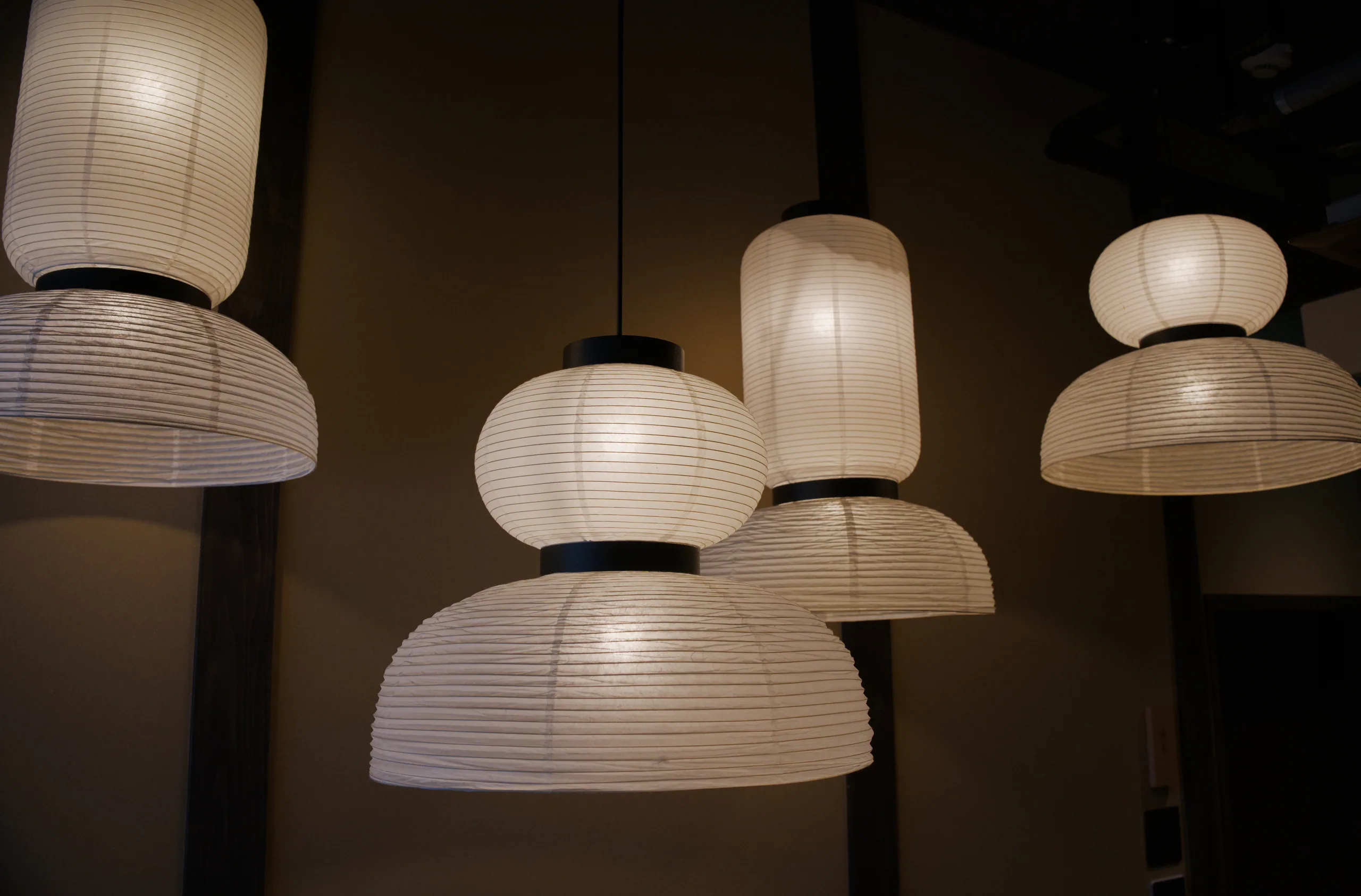 Ribbed paper pendant lights suspended from a dark ceiling.