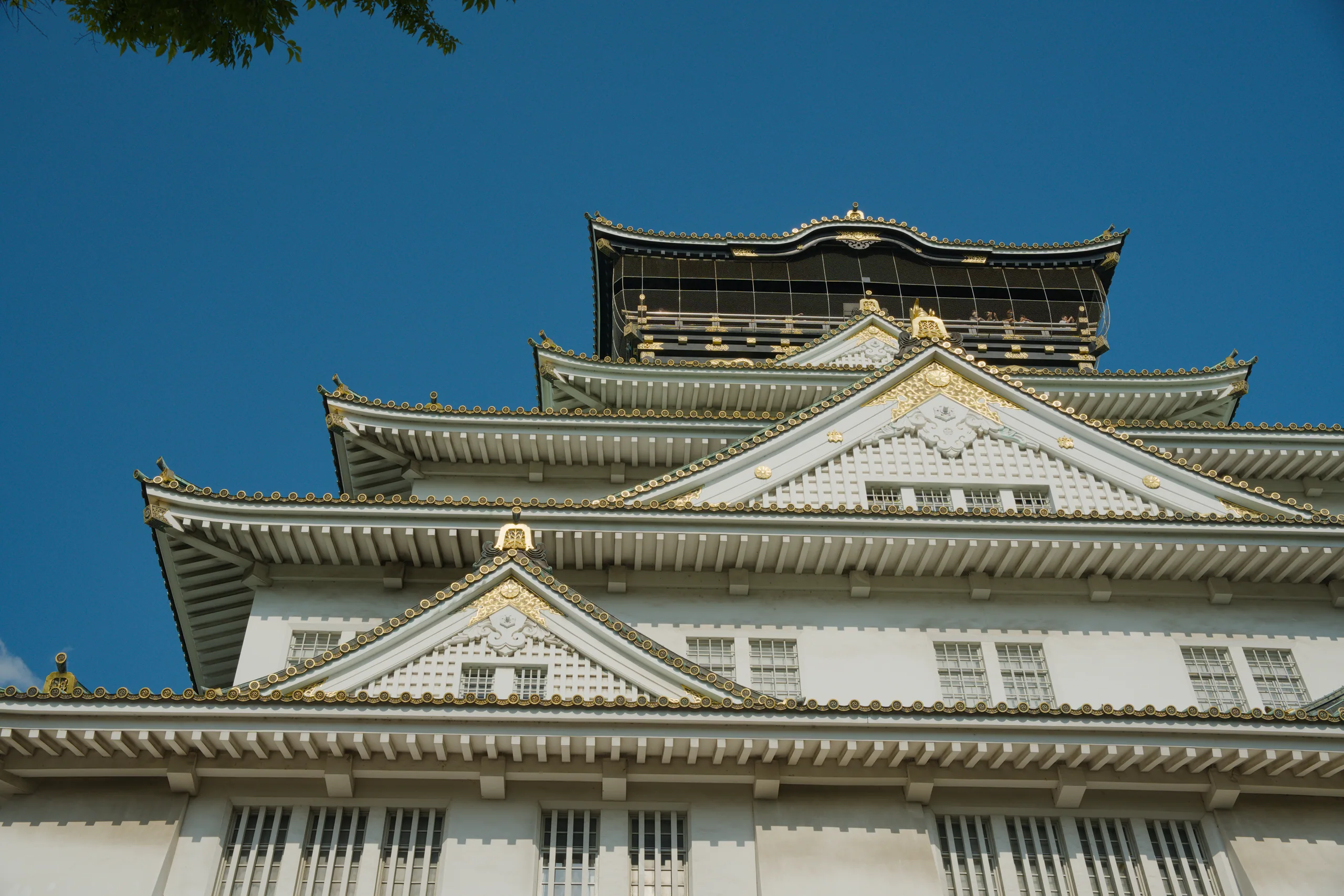 Multi-tiered white and gold castle roofs with black-tiled upper section and upturned eaves.