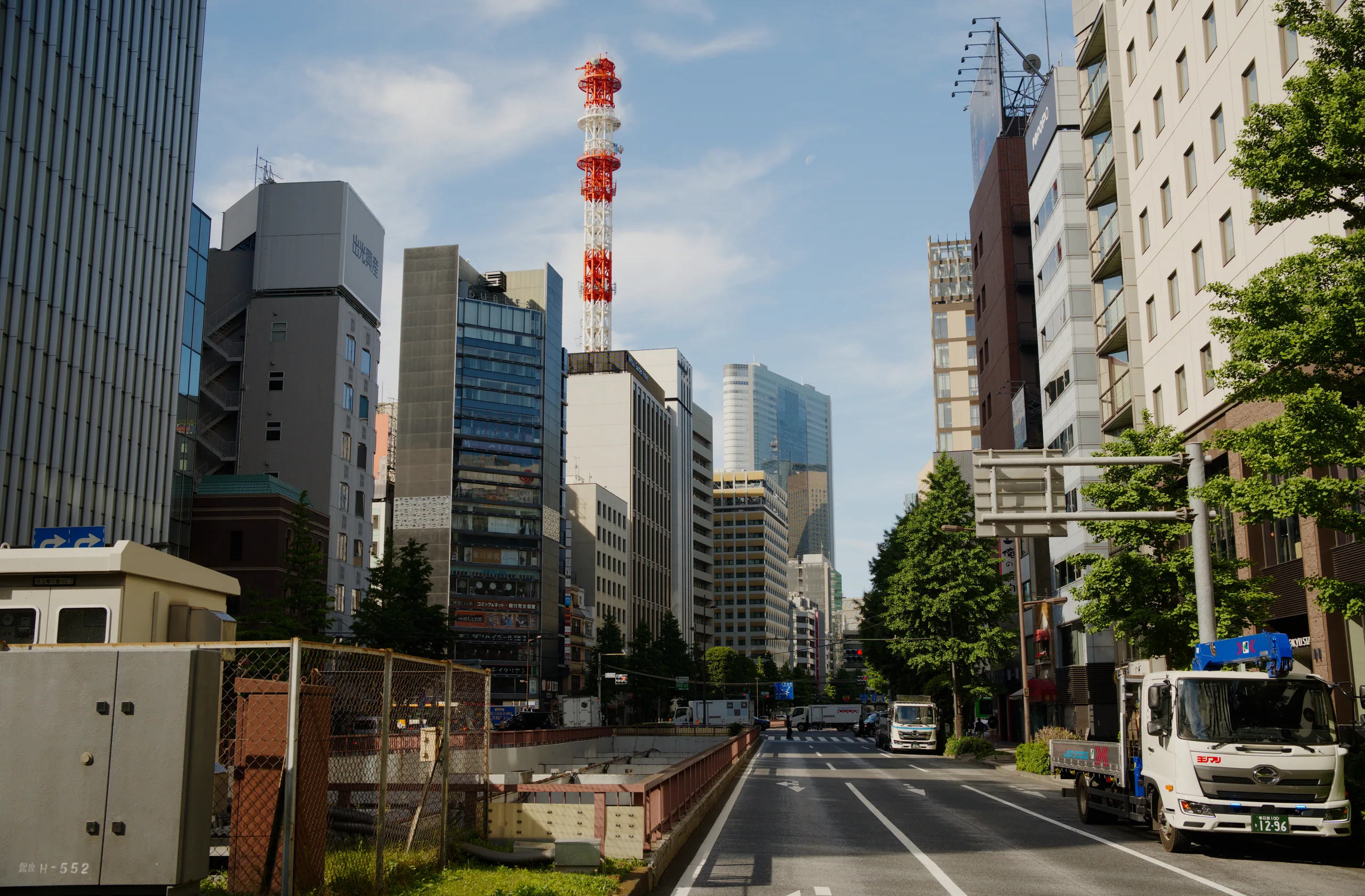 A tall red-and-white striped pole rises from a street lined with modern buildings and cars.