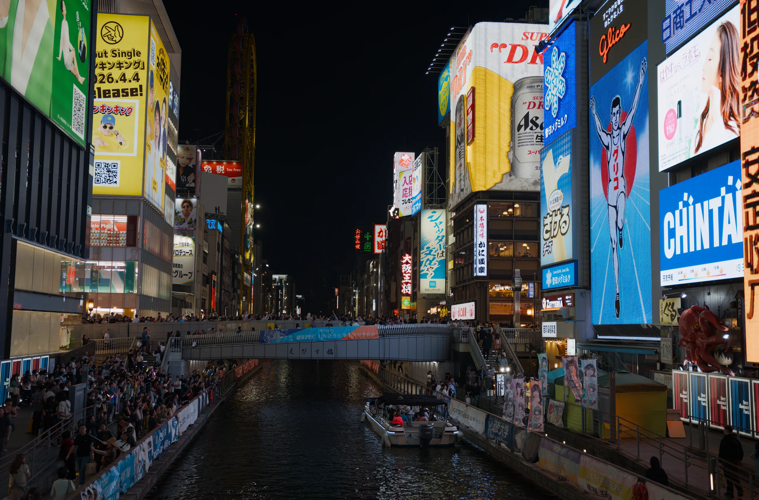 Busy Japanese shopping street at night with neon signage and pedestrian crowds.