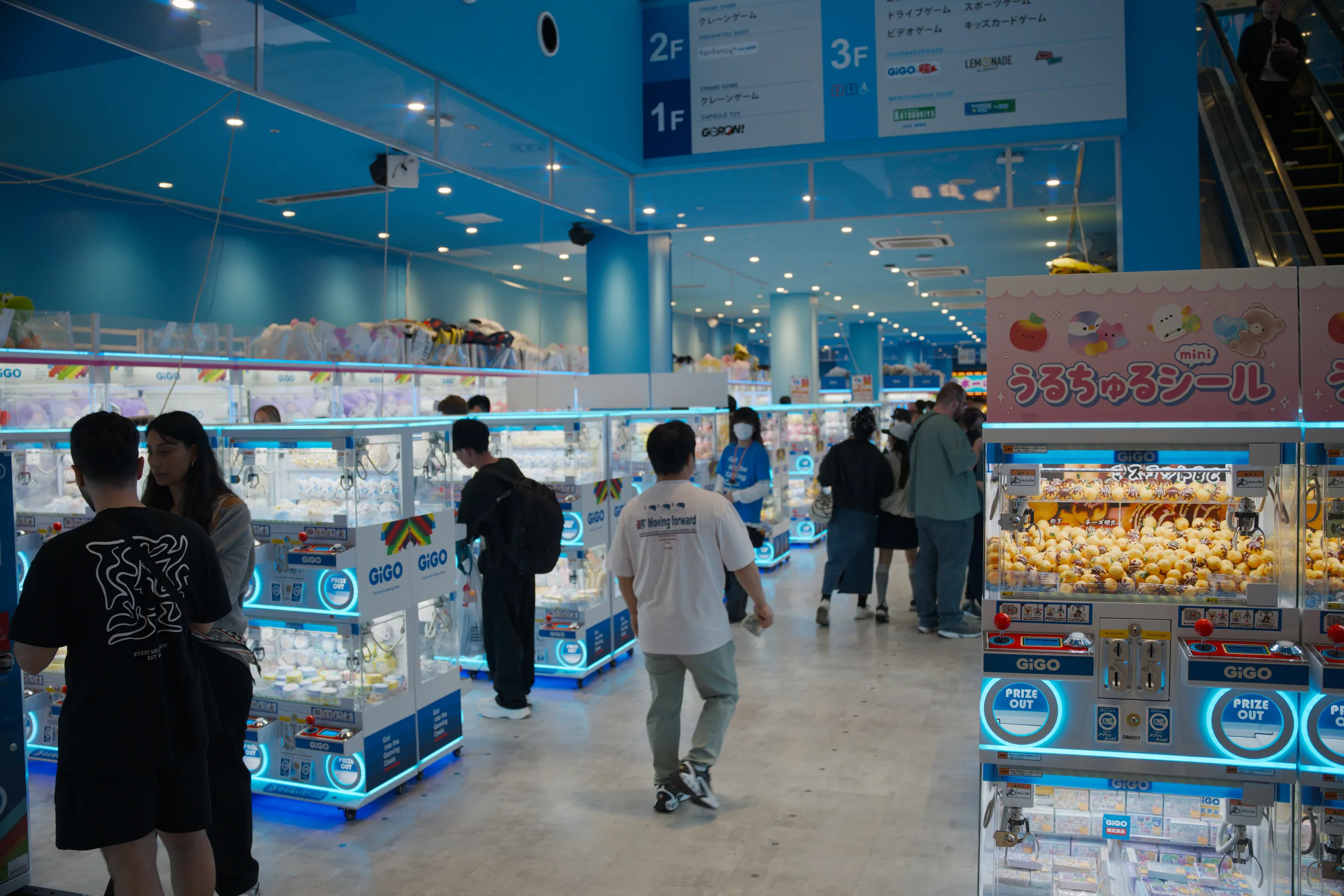 Customers browsing merchandise in a bright blue-lit retail space with illuminated display cases.
