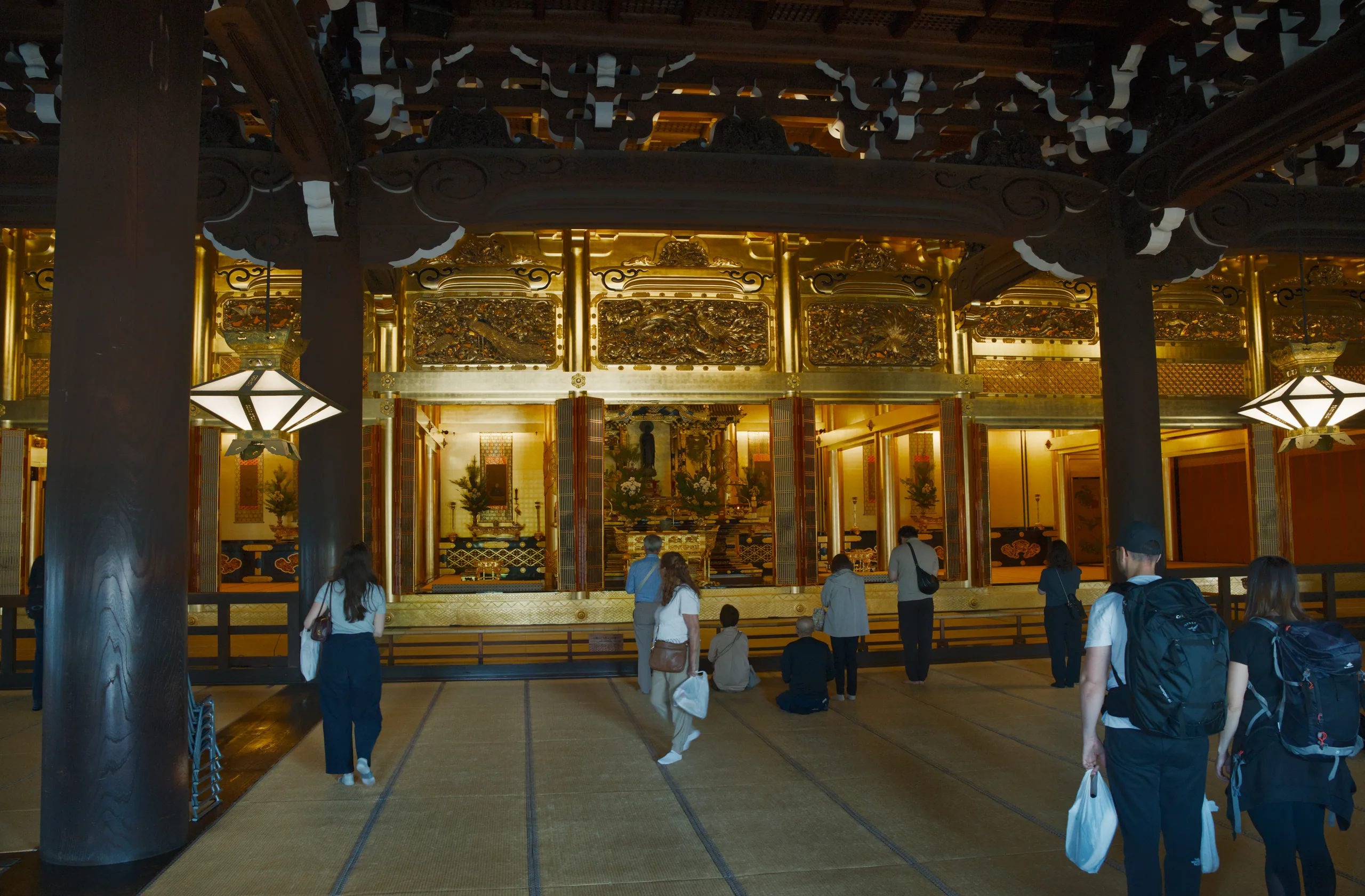 Illuminated interior corridor with glass storefront and pedestrians passing through.