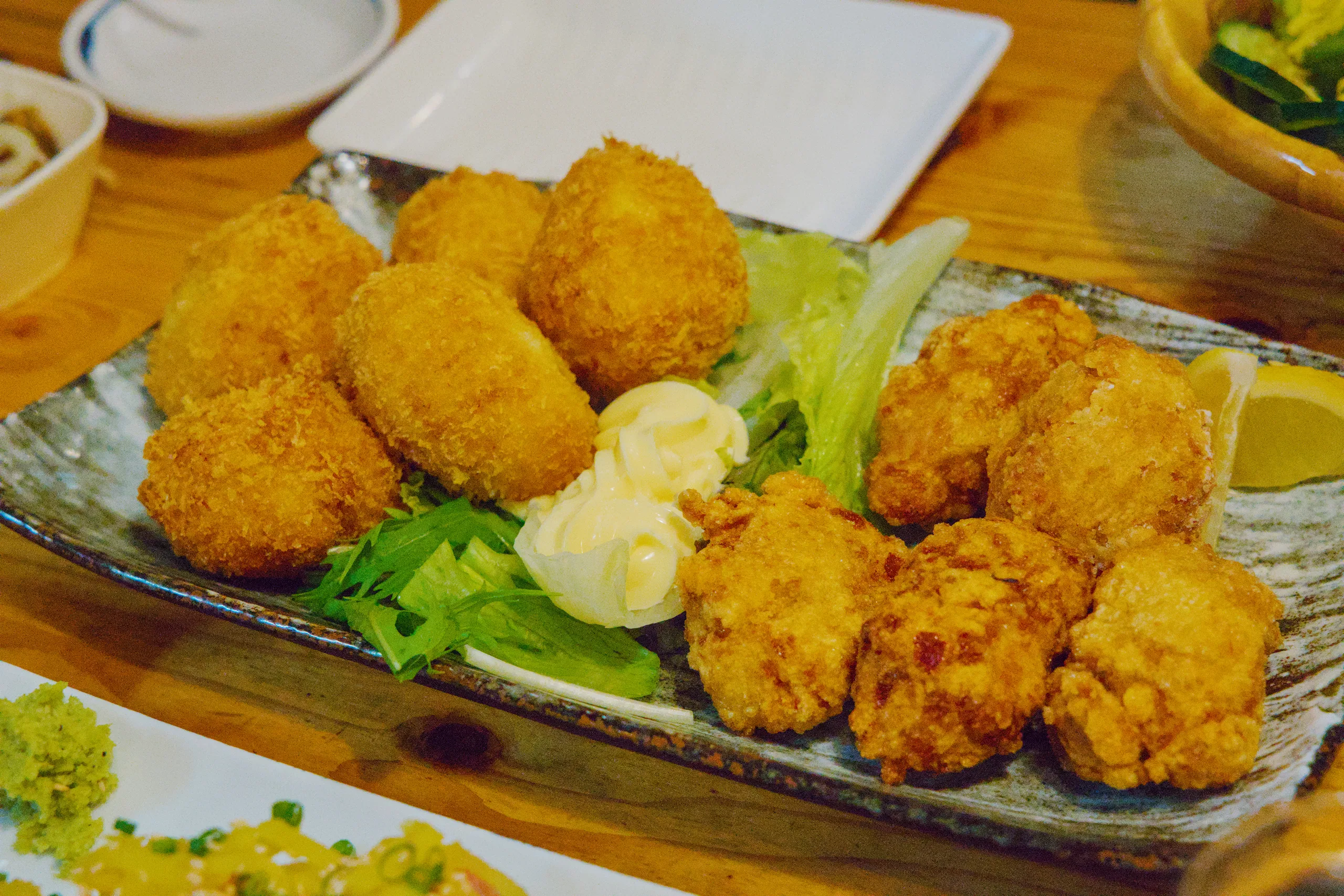 Golden fried balls with lettuce and pickled ginger garnish on a plate.
