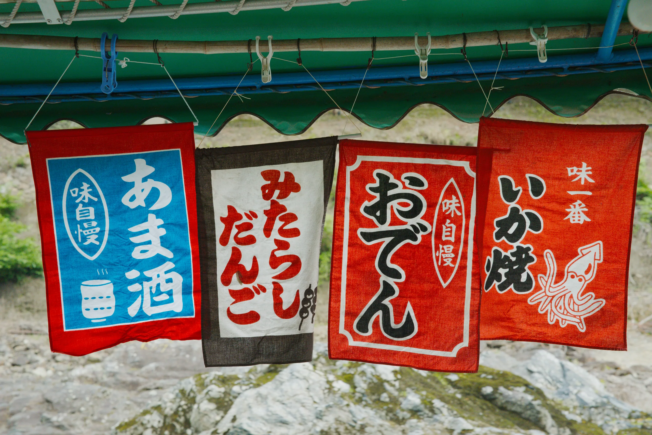 Red and white Japanese merchant signs hang above moored boats on the river.