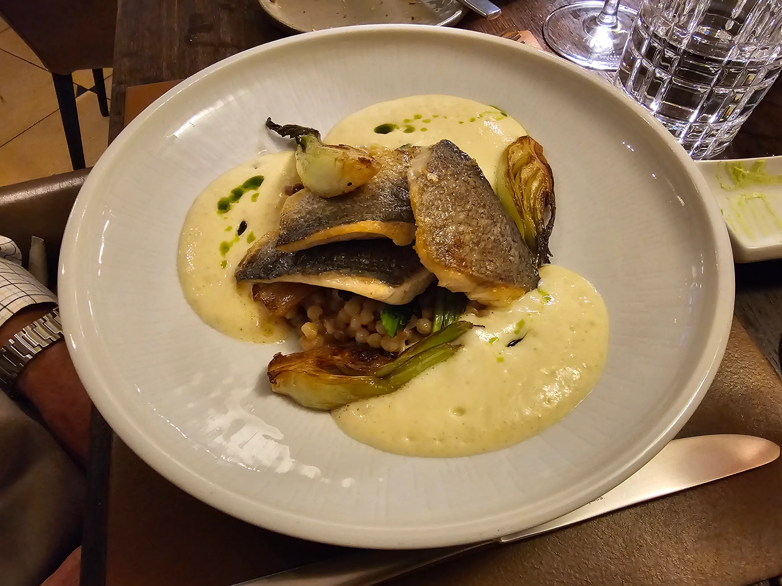 A fillet of crisp-skinned fish on pearl barley with charred onion in a pale sauce.