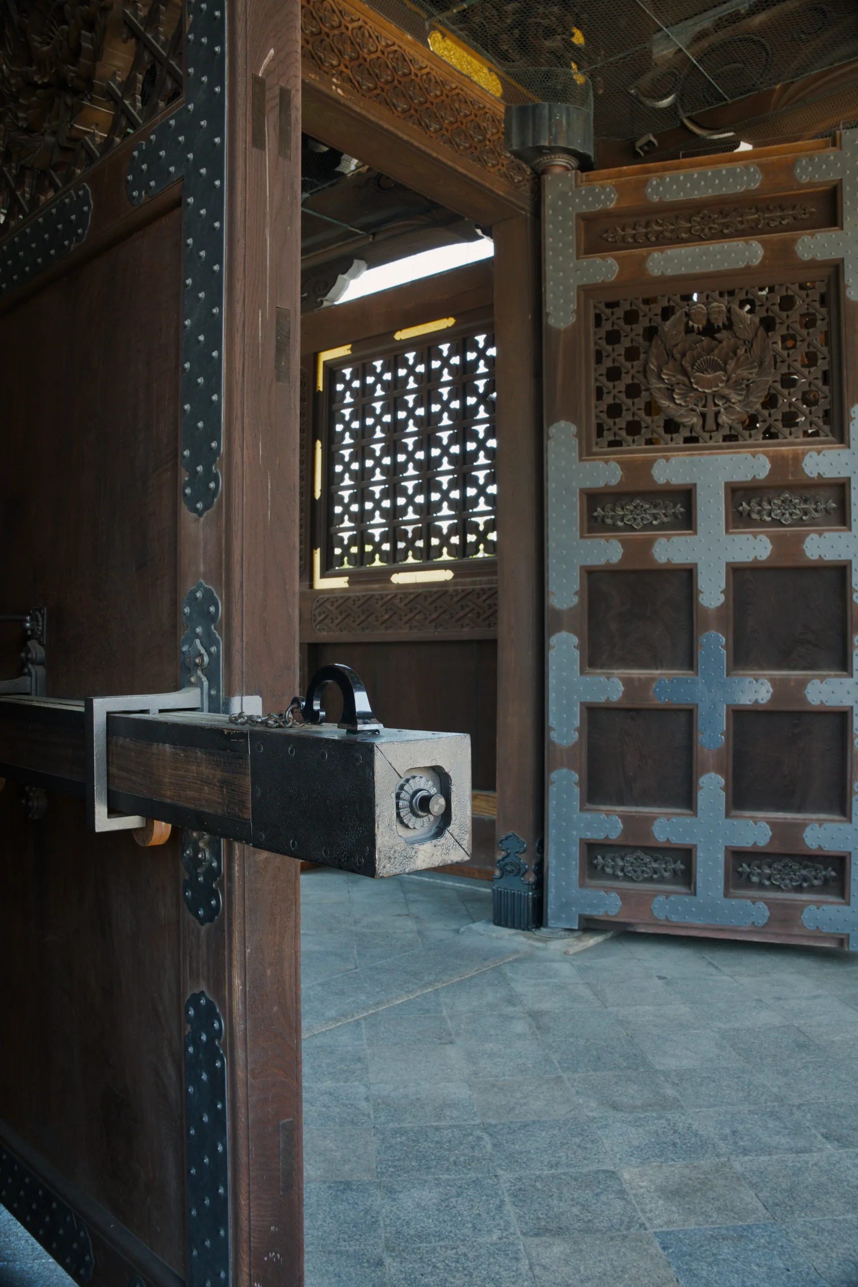 Interior of a wooden temple with ornate lattice screens and carved decorative details.