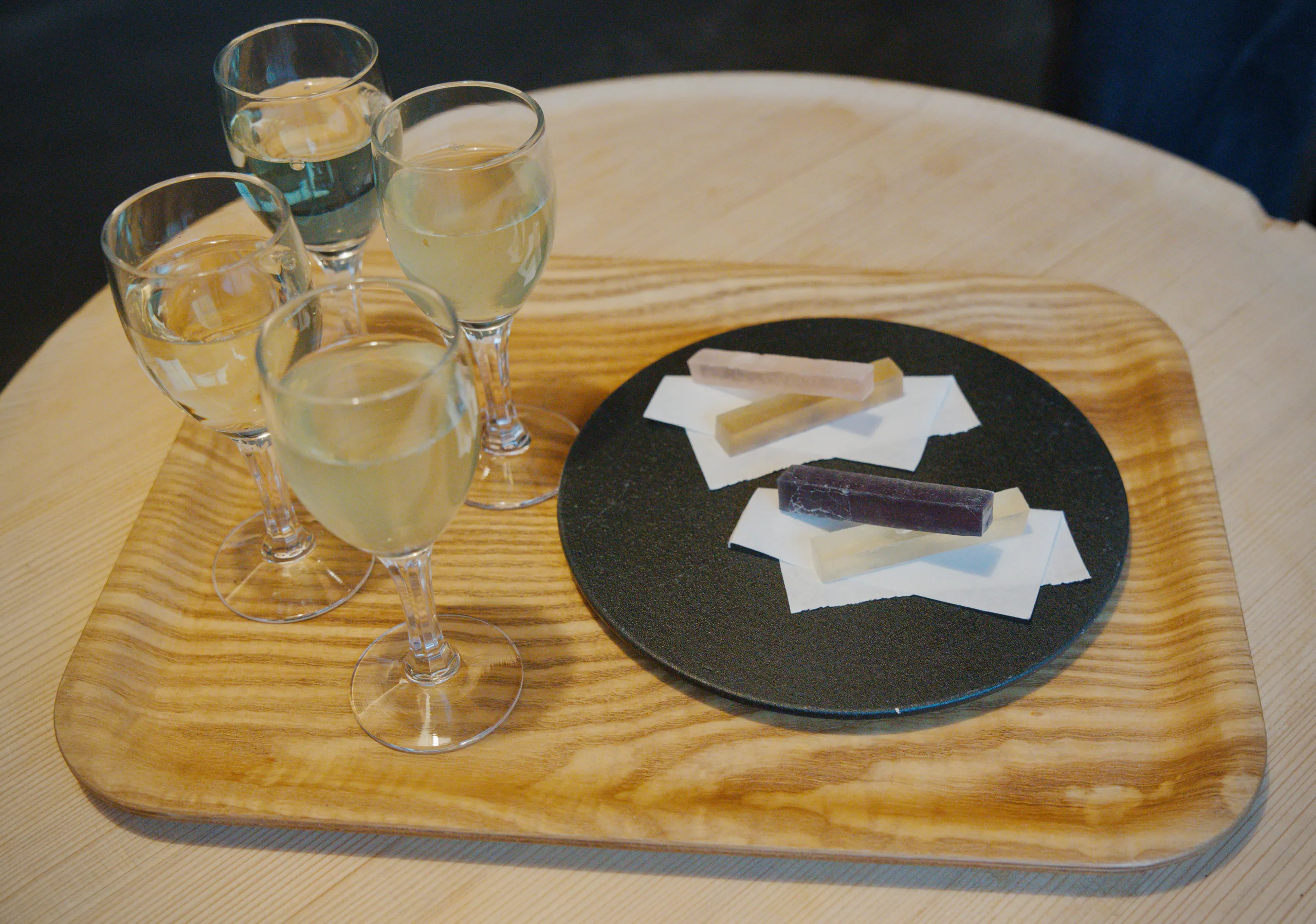 Table setting with water glasses and folded white napkins on a wooden board.