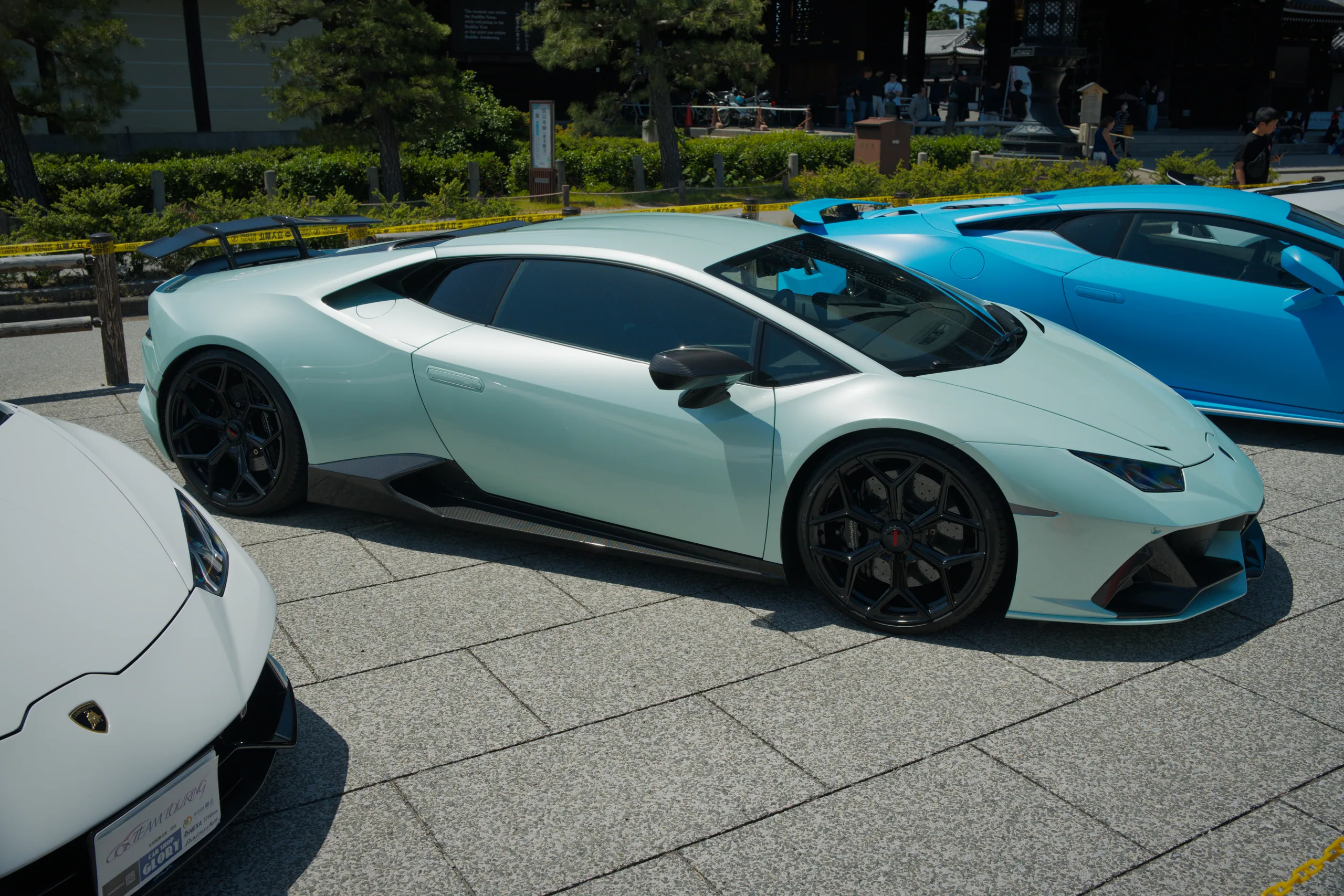 A white sports car sits on a paved exhibition area at a car show venue.