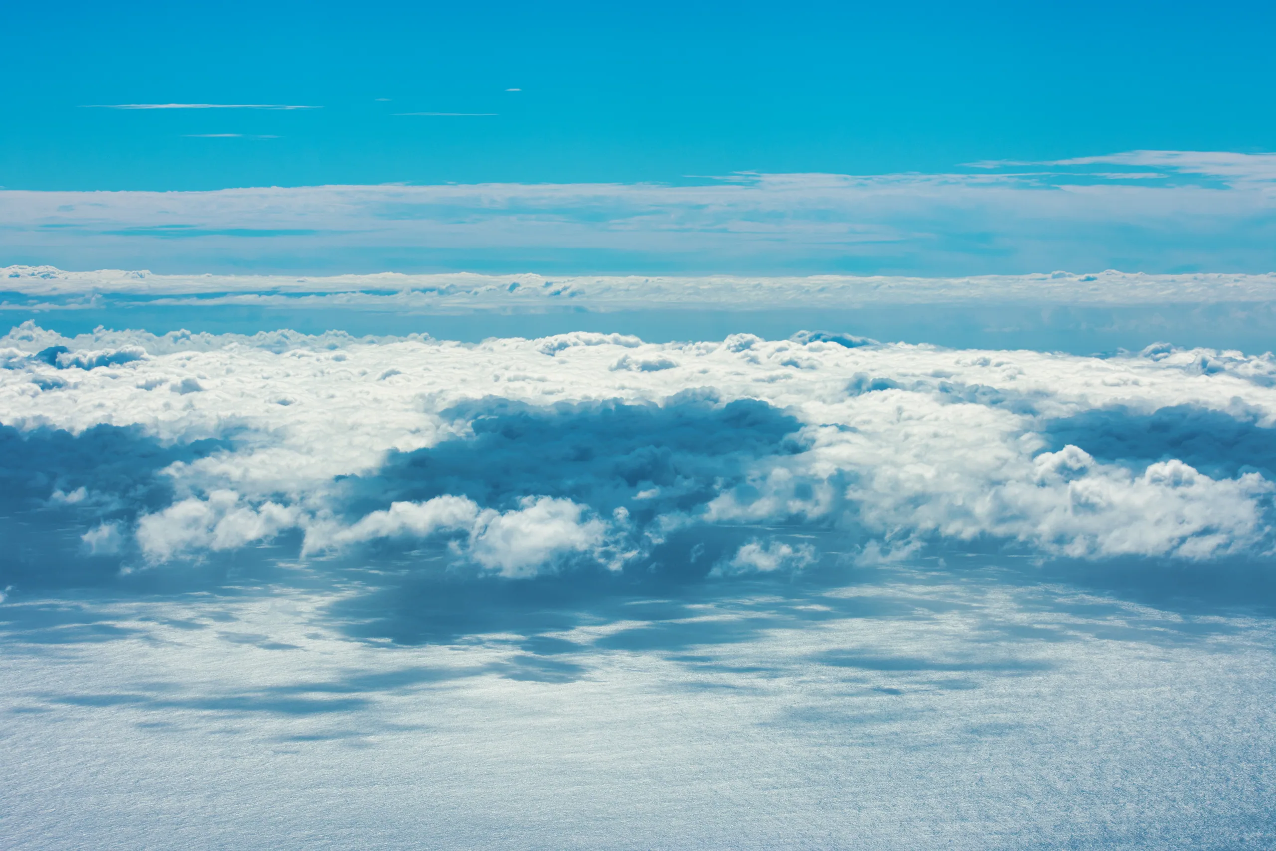 A flat sea of white cloud seen from above, lit pale blue, with clear sky beyond.