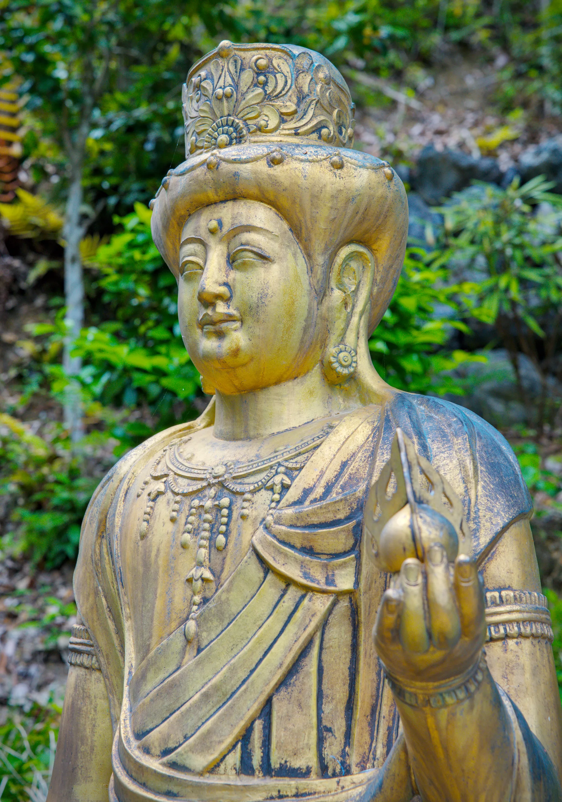 A gilded Buddha statue carved in ornate robes and jewelry with an elaborate crown.
