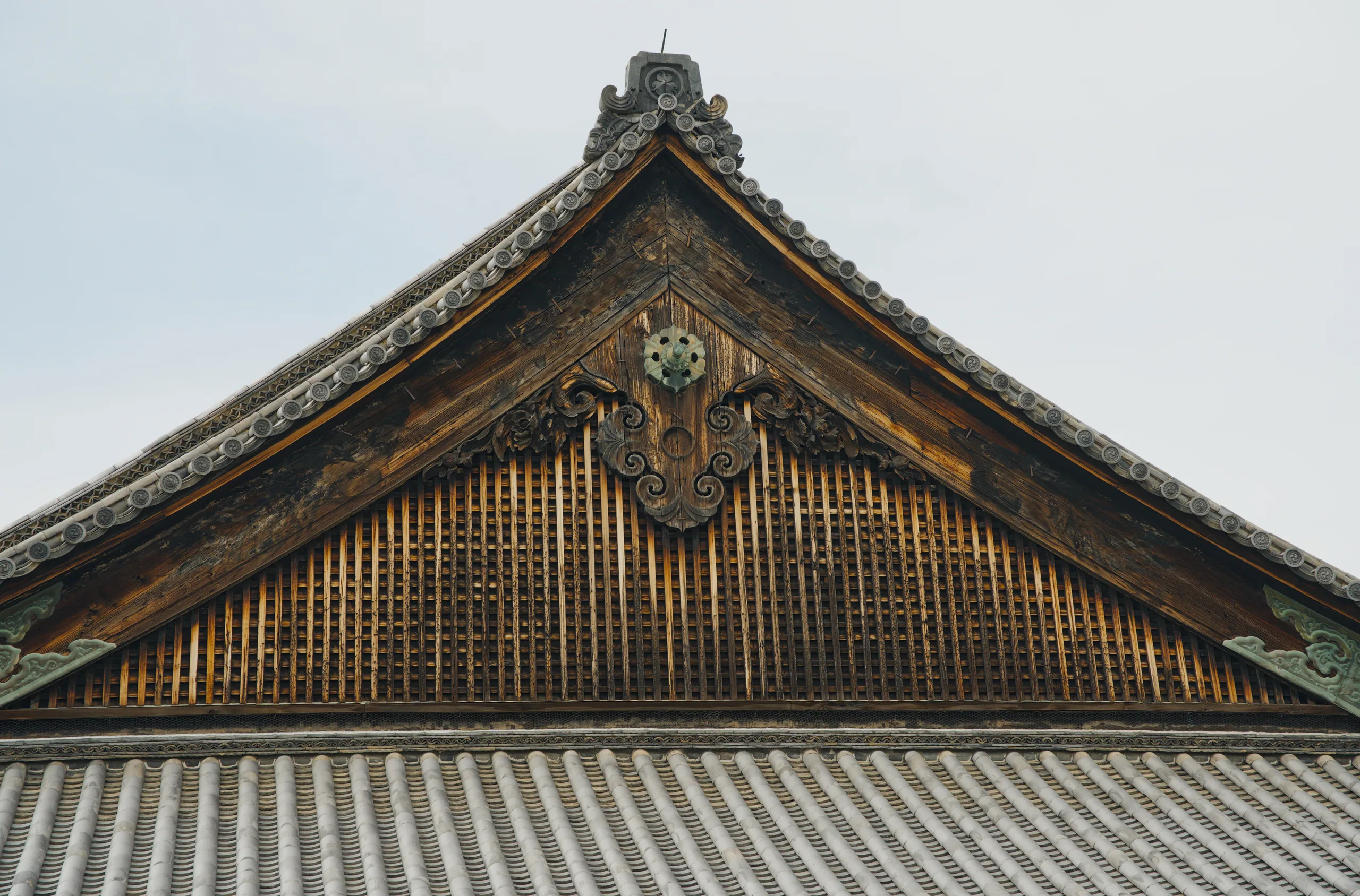 Japanese temple gable with ornate carved decoration and a hanging textured wooden panel.