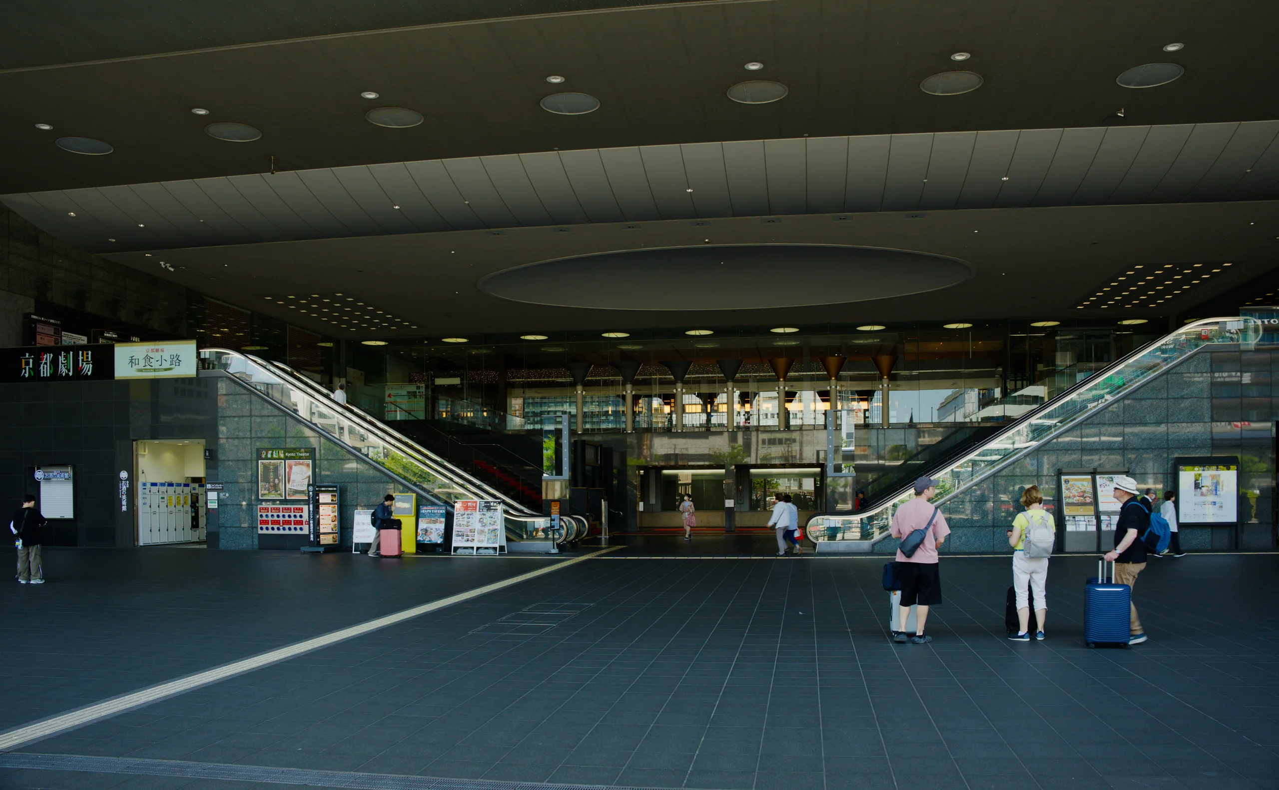 A modern station interior with wide stairs, recessed ceiling lighting, and a striped floor.