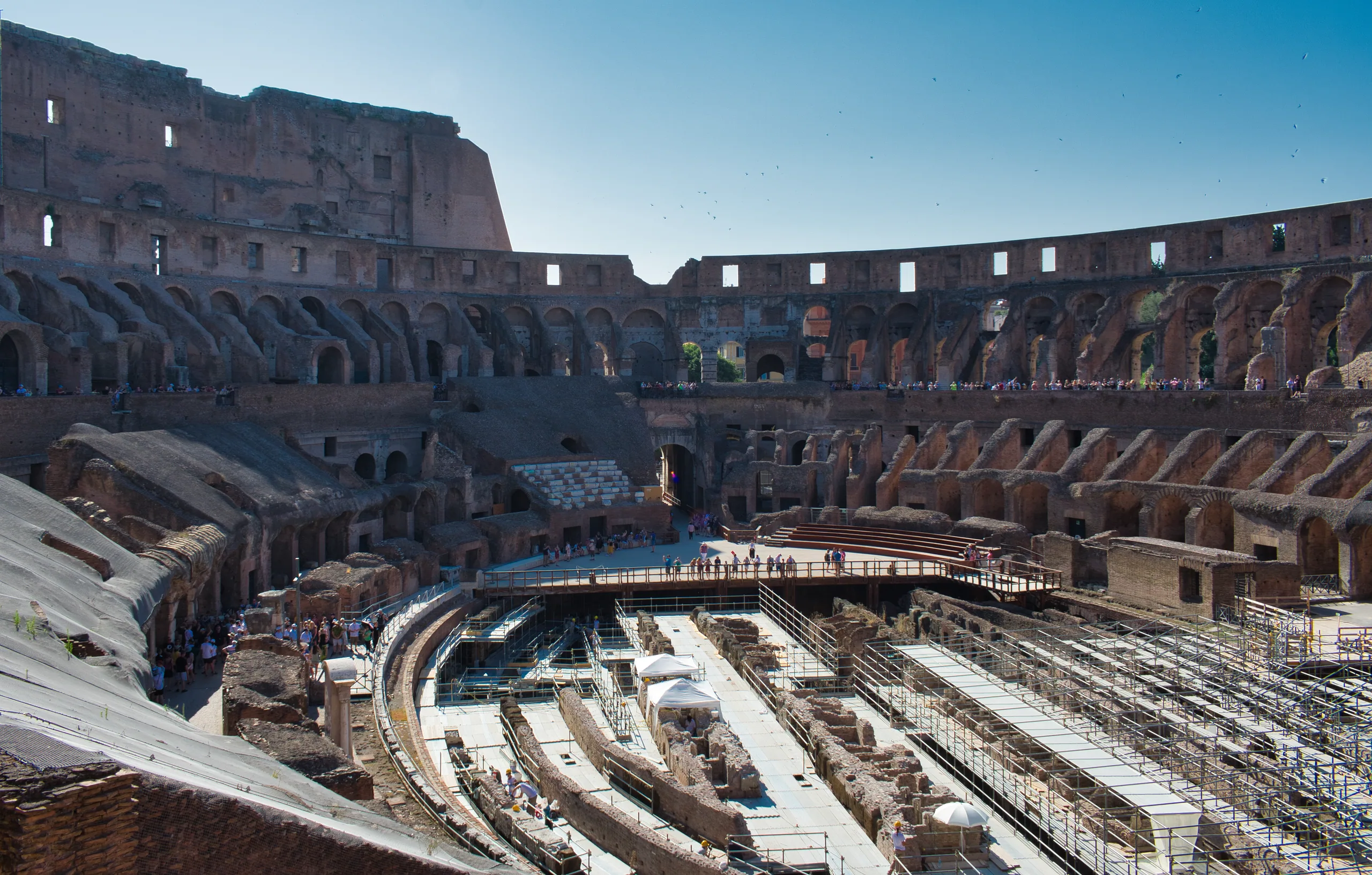 The interior of the Colosseum from the upper tier, the exposed hypogeum passages and tiered seating curving away.