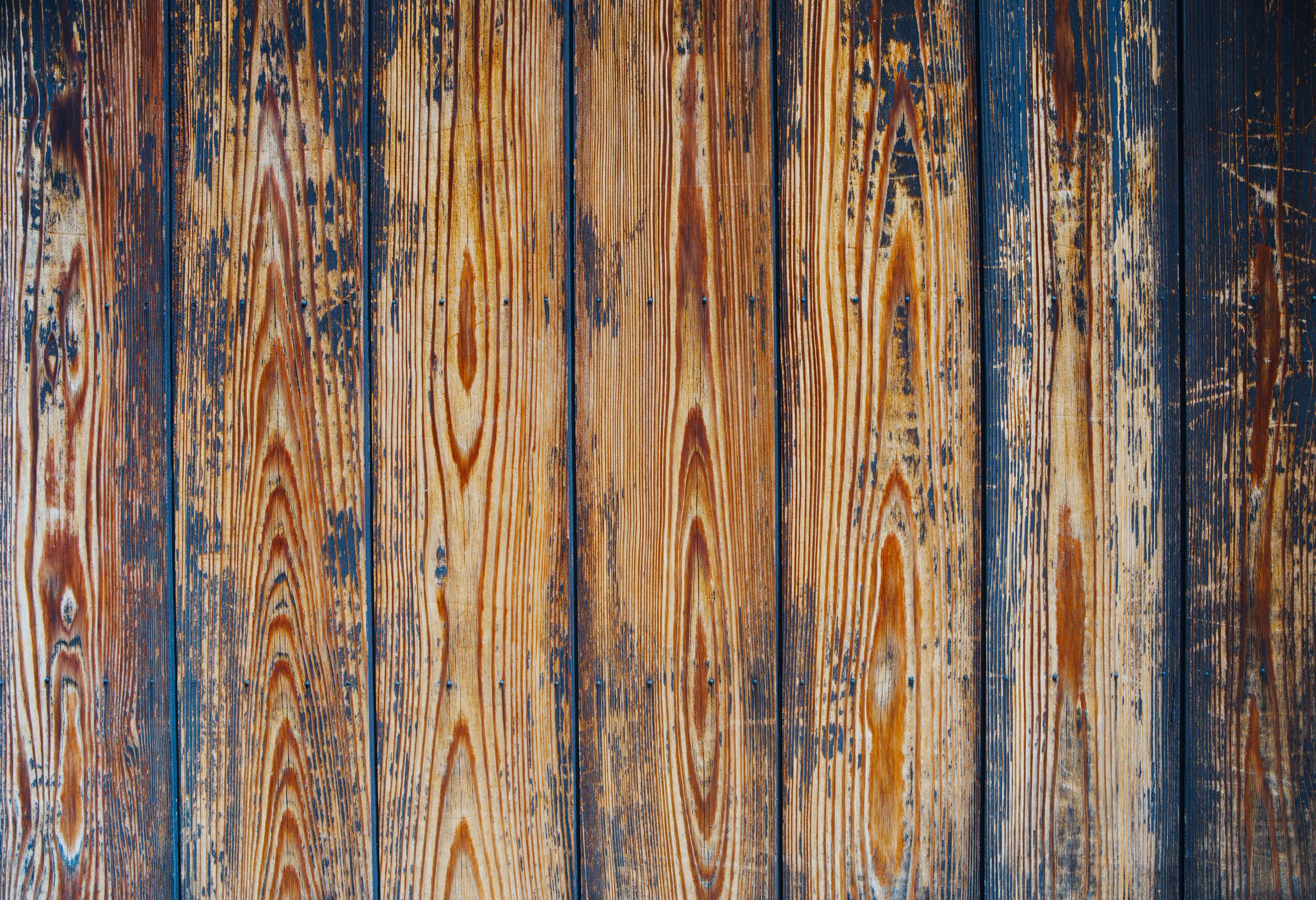 Weathered wood boards showing grain texture with faded blue and golden paint.