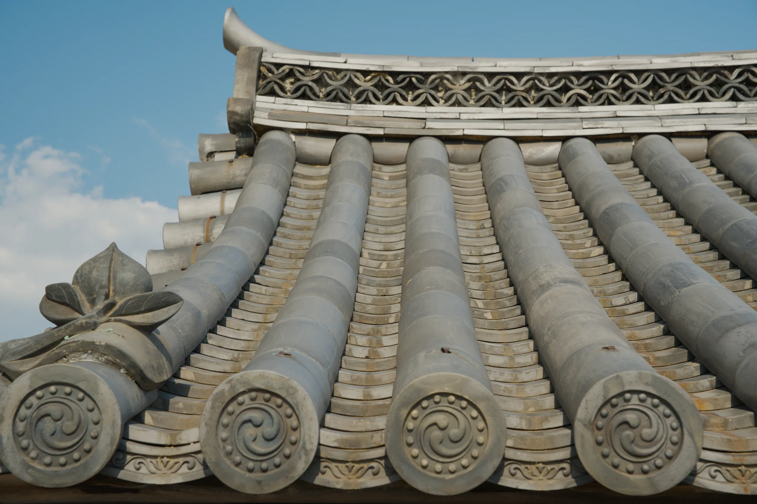 Ornate white ceramic roof eaves with curved tiles and carved circular decorative elements.