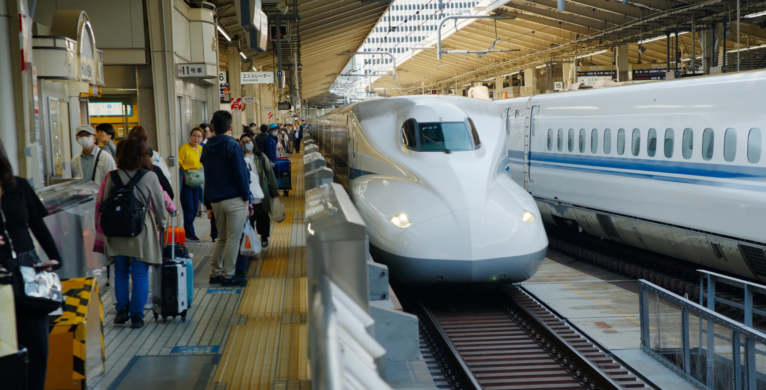Passengers with luggage boarding a shinkansen at a platform.
