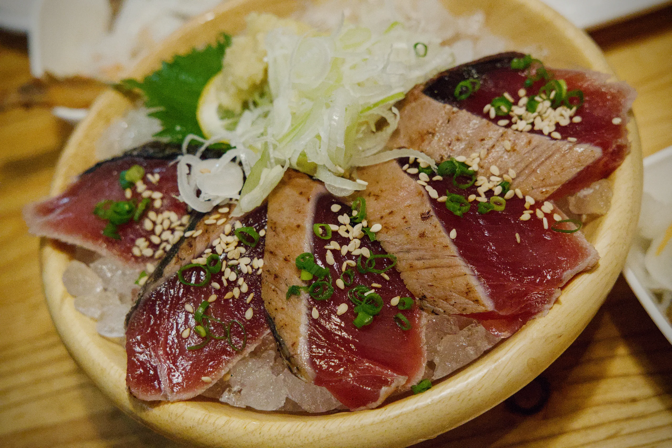 Sliced raw fish and daikon arranged on a ceramic plate with sesame seeds.