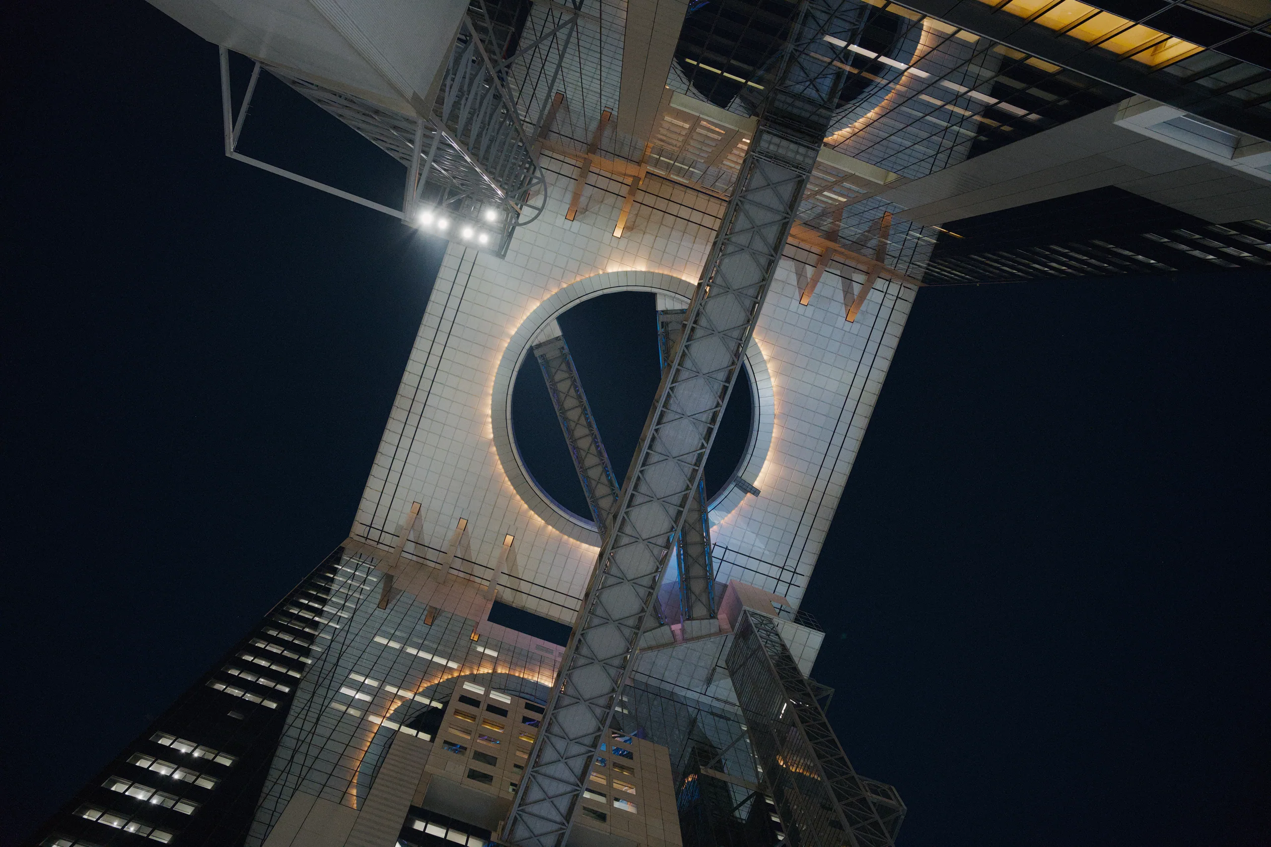Lit building facades rise at a steep upward angle against the night sky.