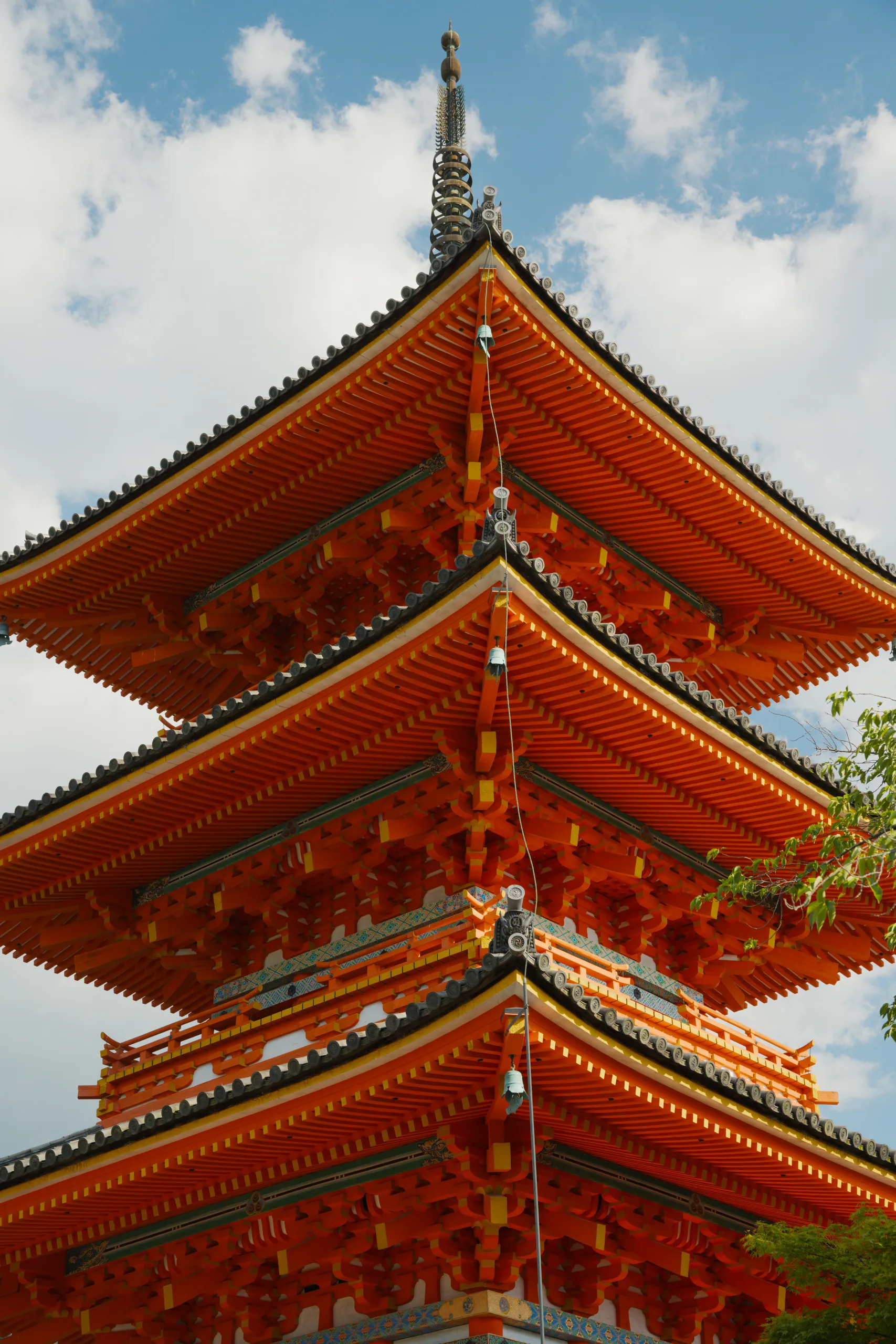 Stacked lacquered roof tiers of a Japanese pagoda against a white sky.