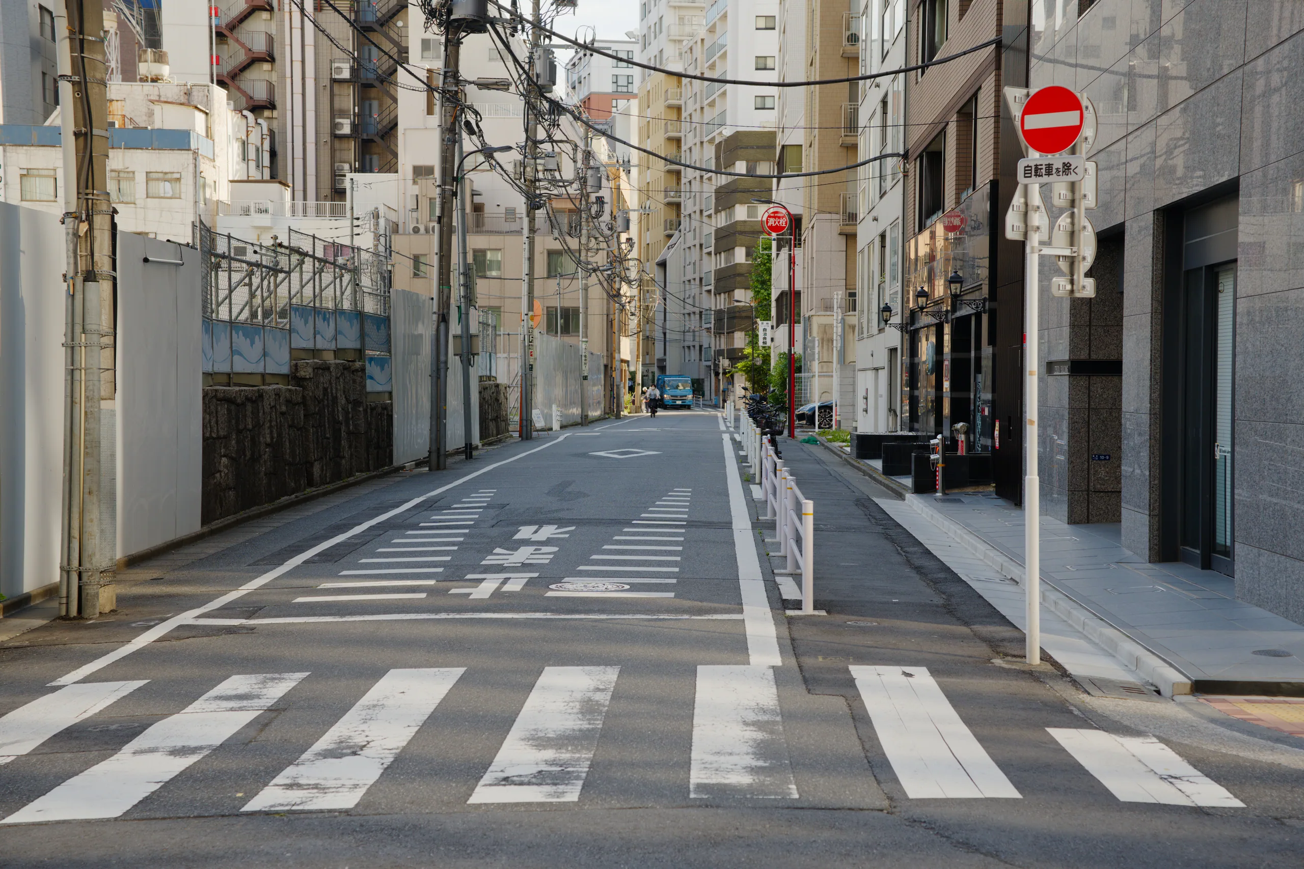 A residential street with a zebra crossing and older apartment buildings lining both sides.
