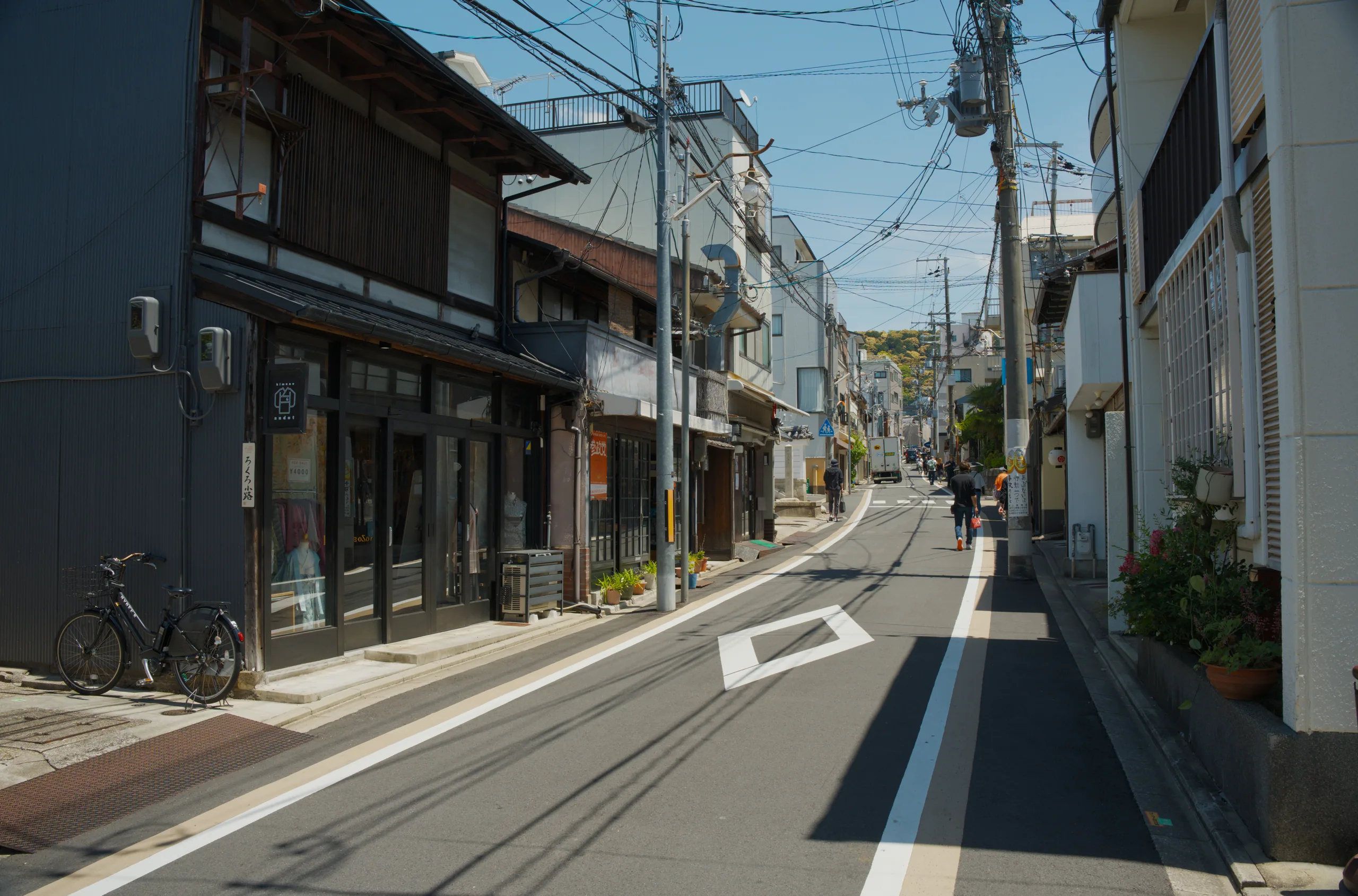 A quiet street lined with traditional single-story buildings under a clear sky with overhead power lines.
